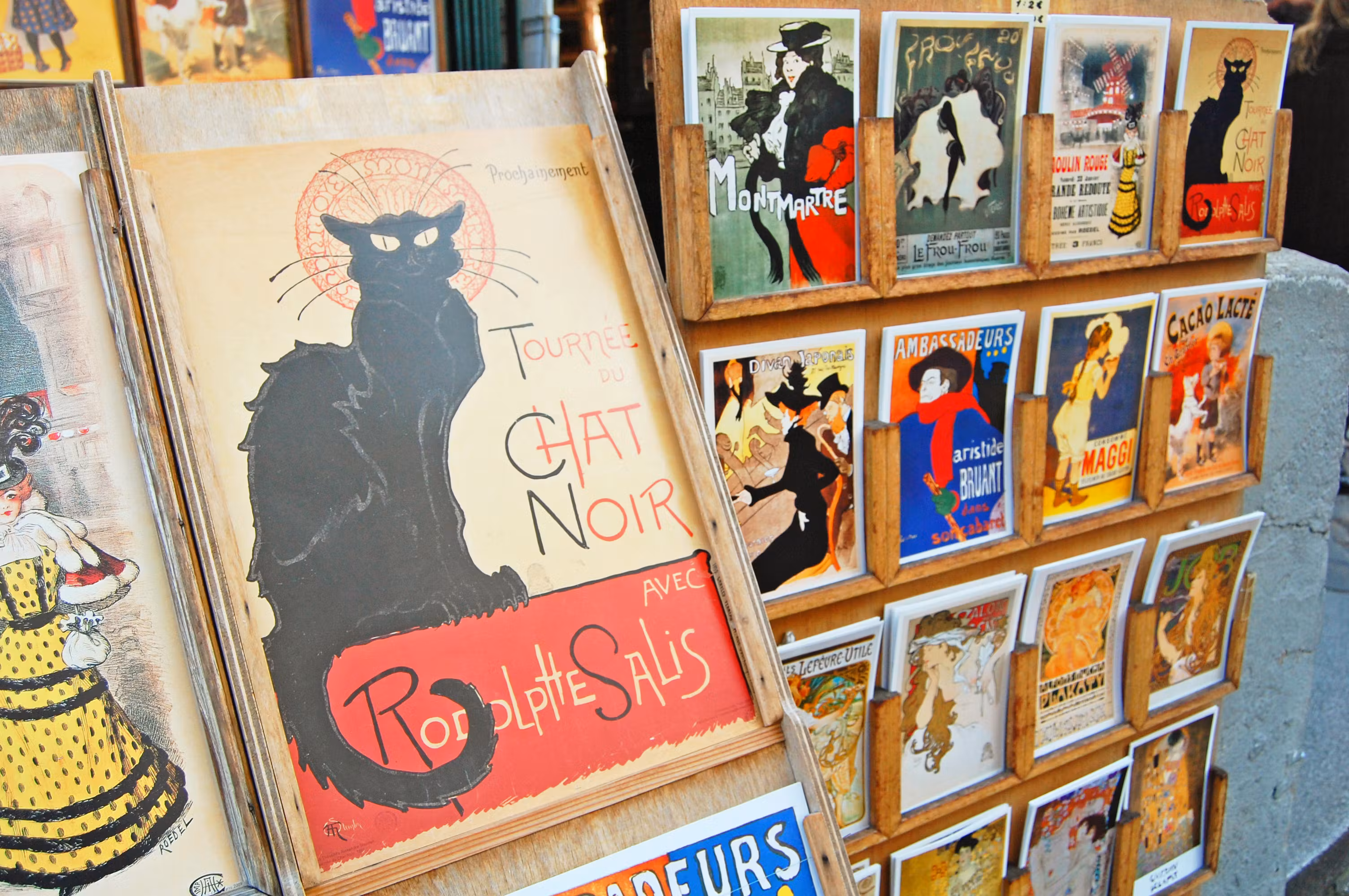 Affiches rétro de Montmartre, dont l'emblématique affiche 'Tournée du Chat Noir' de Rodolphe Salis, exposées dans un présentoir à Paris